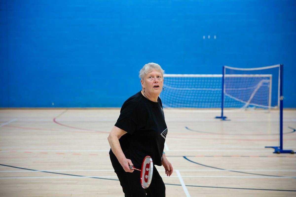 Older woman playing badminton in a sports hall